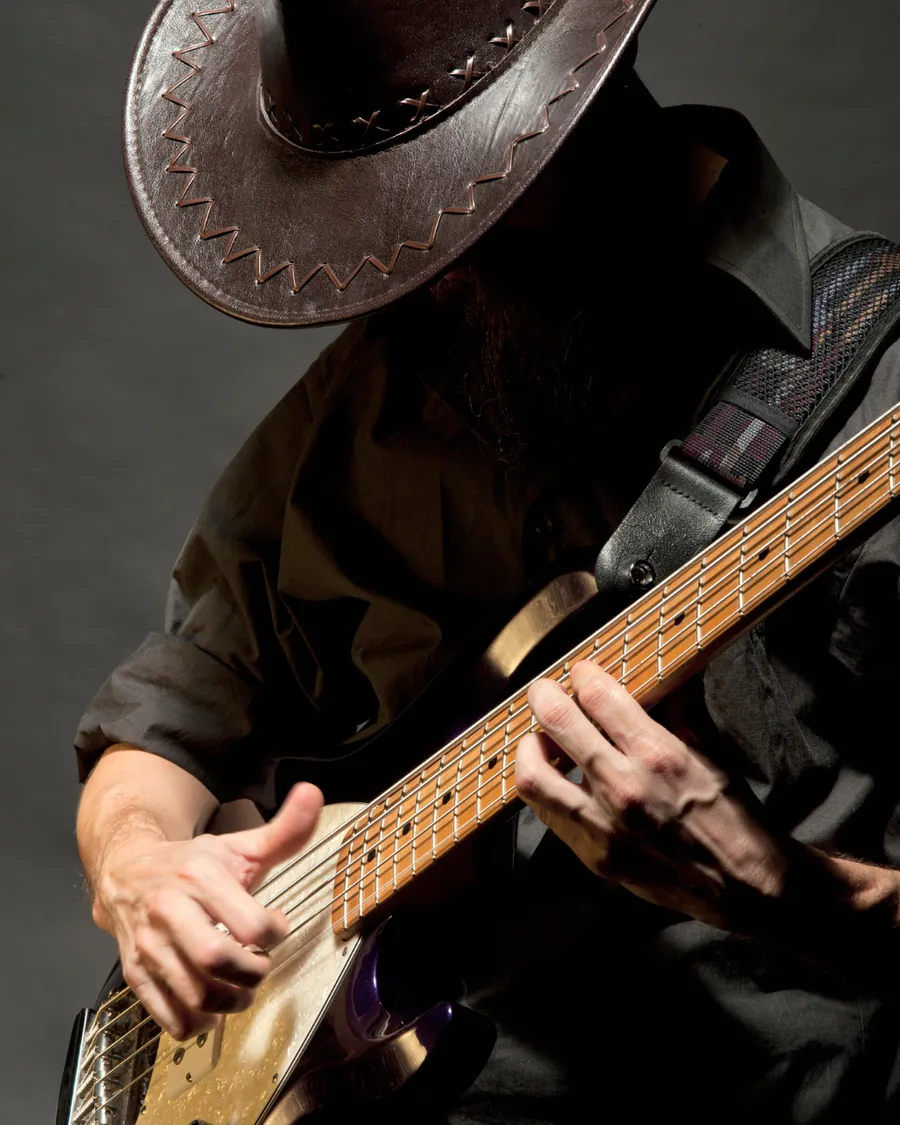 Hands playing a bajo quinto under low light
